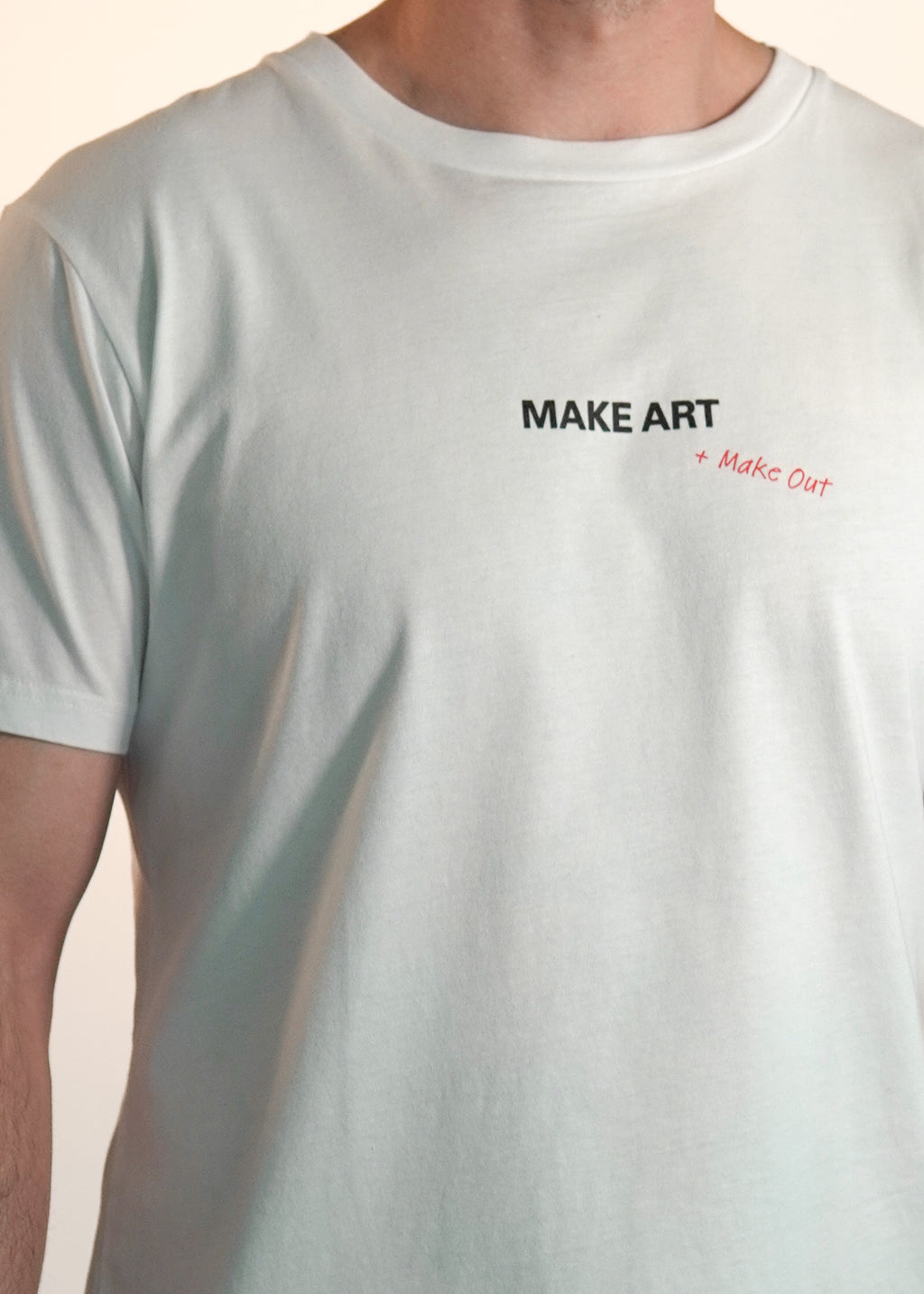 White t-shirt with 'MAKE ART + Make Out' text on a plain background