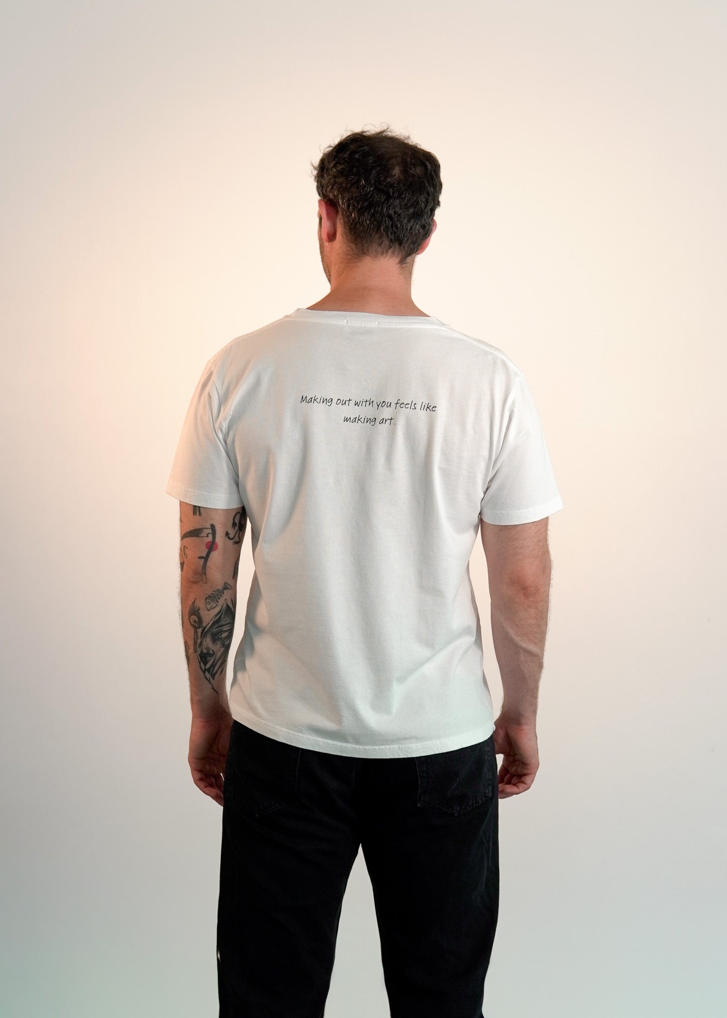 Person wearing a white t-shirt with text on the back against a plain background