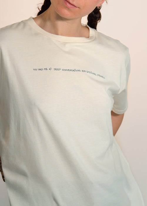 Person wearing a beige t-shirt with text on a plain background